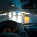 Senior driver experiencing headlight glare and halos at night, a common symptom of worsening cataracts.